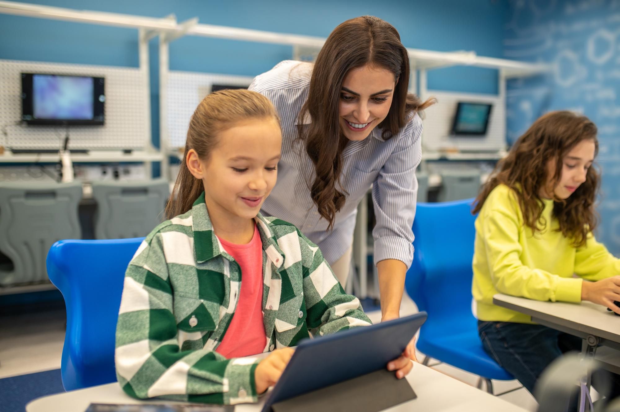 Teacher guiding students on tablets to encourage positive digital behavior.