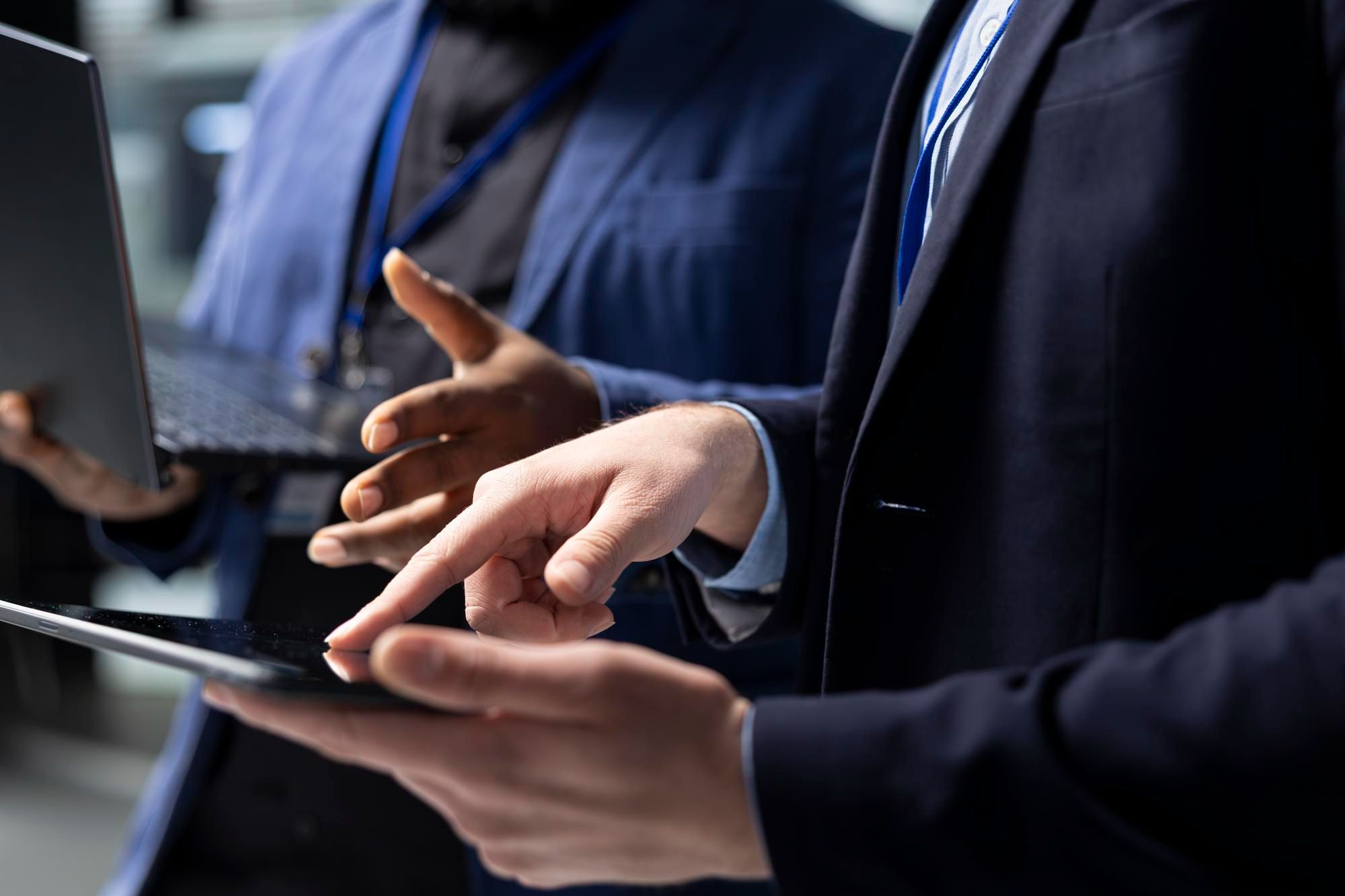 Two professionals in business suits using a tablet and laptop, symbolizing digital collaboration and modernization in government services through eGovernment initiatives.