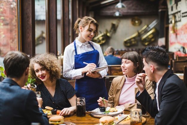 A restaurant waitress taking customer orders as part of a great dining experience supported by a loyalty management system in the F&B industry
