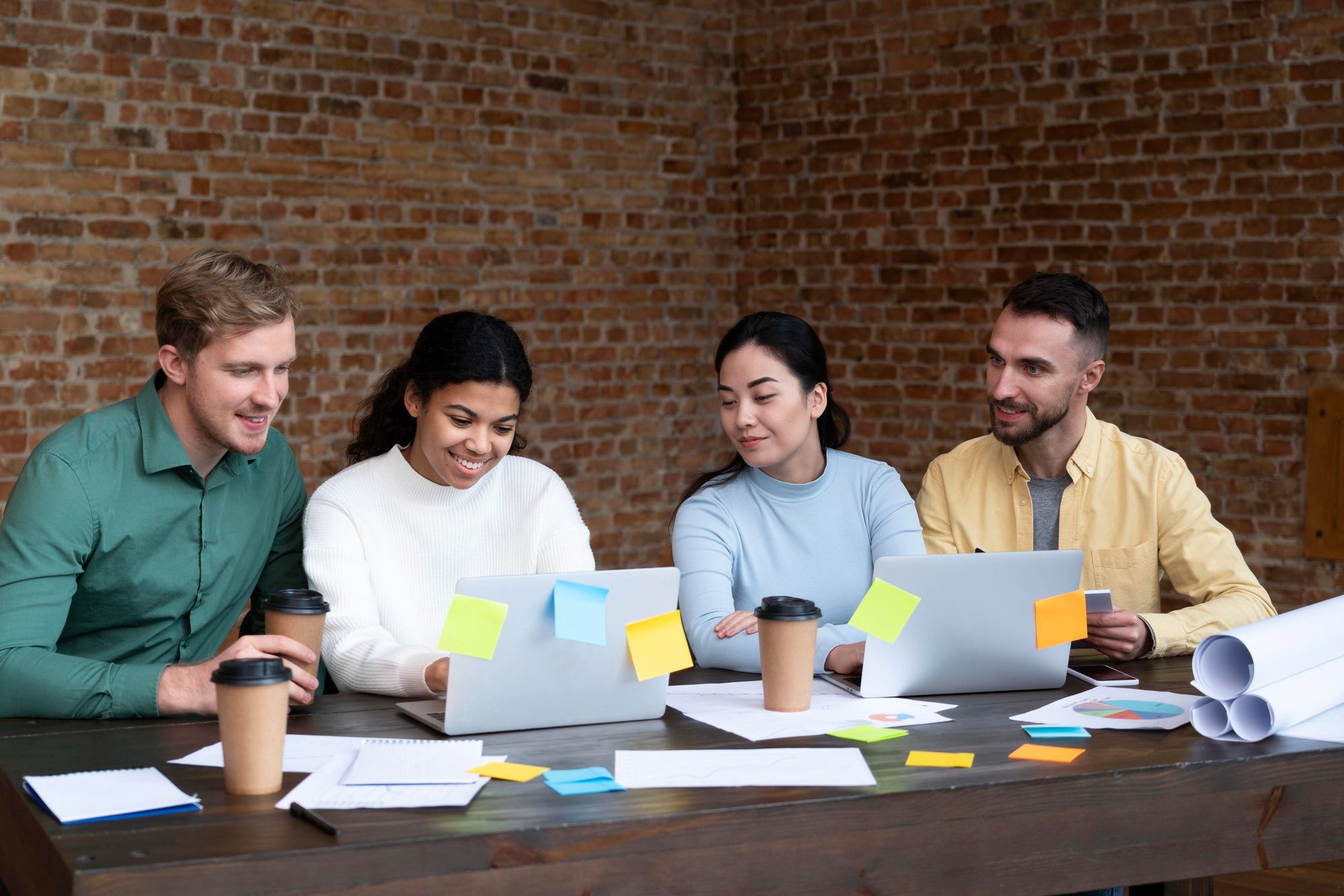 IT team collaborating in a casual office environment, discussing ideas with laptops and sticky notes, representing fast-paced communication culture in the tech industry.